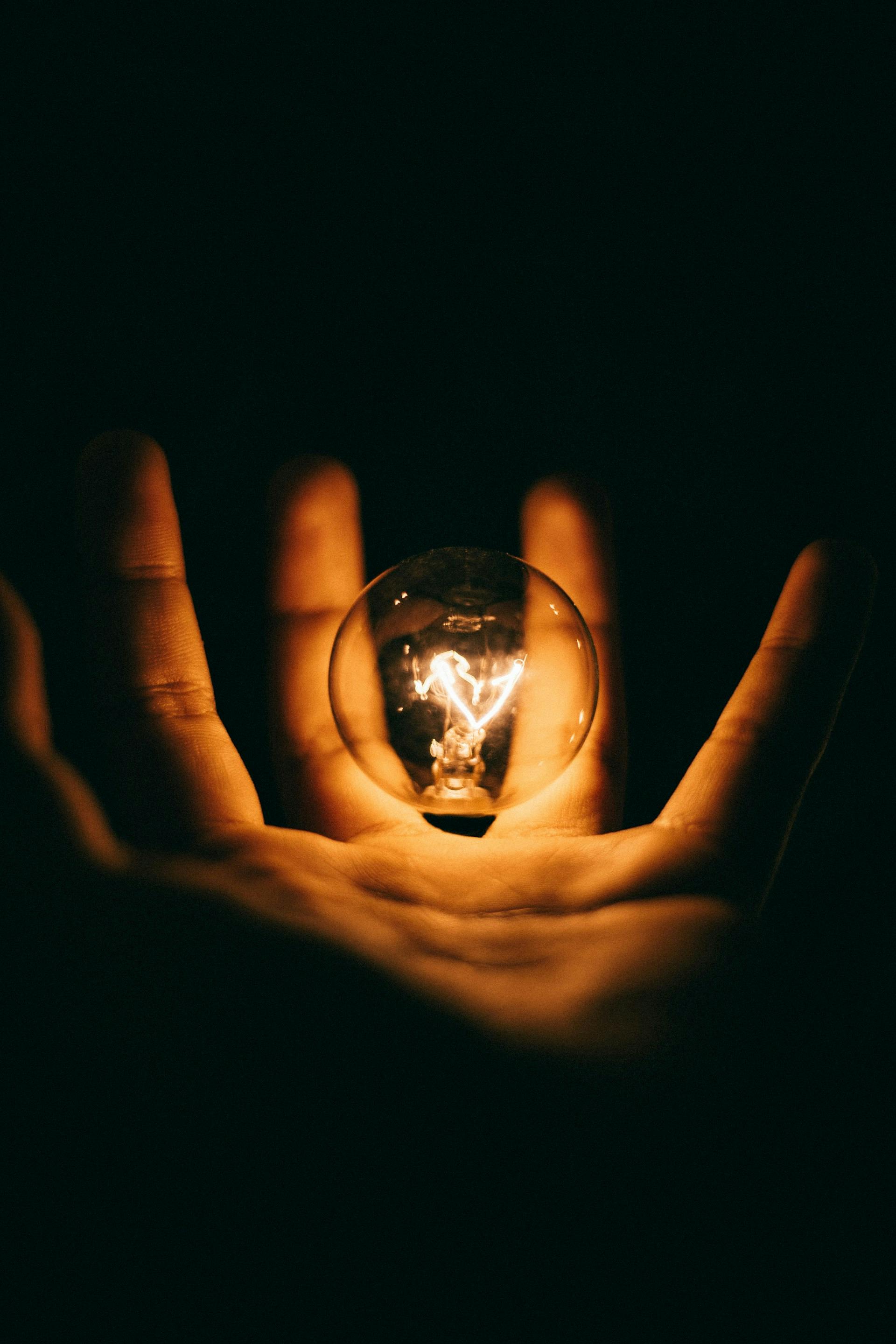 Person holding a glass bulb in their palm